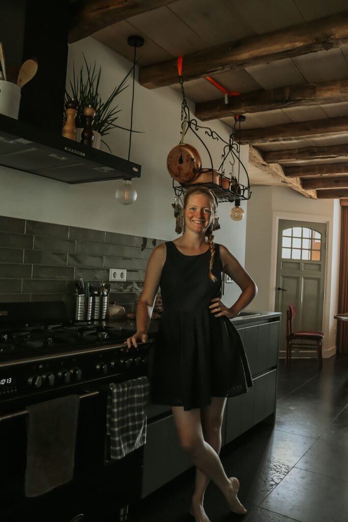 Vrouw in landelijke keuken met koperen pannen aan rek